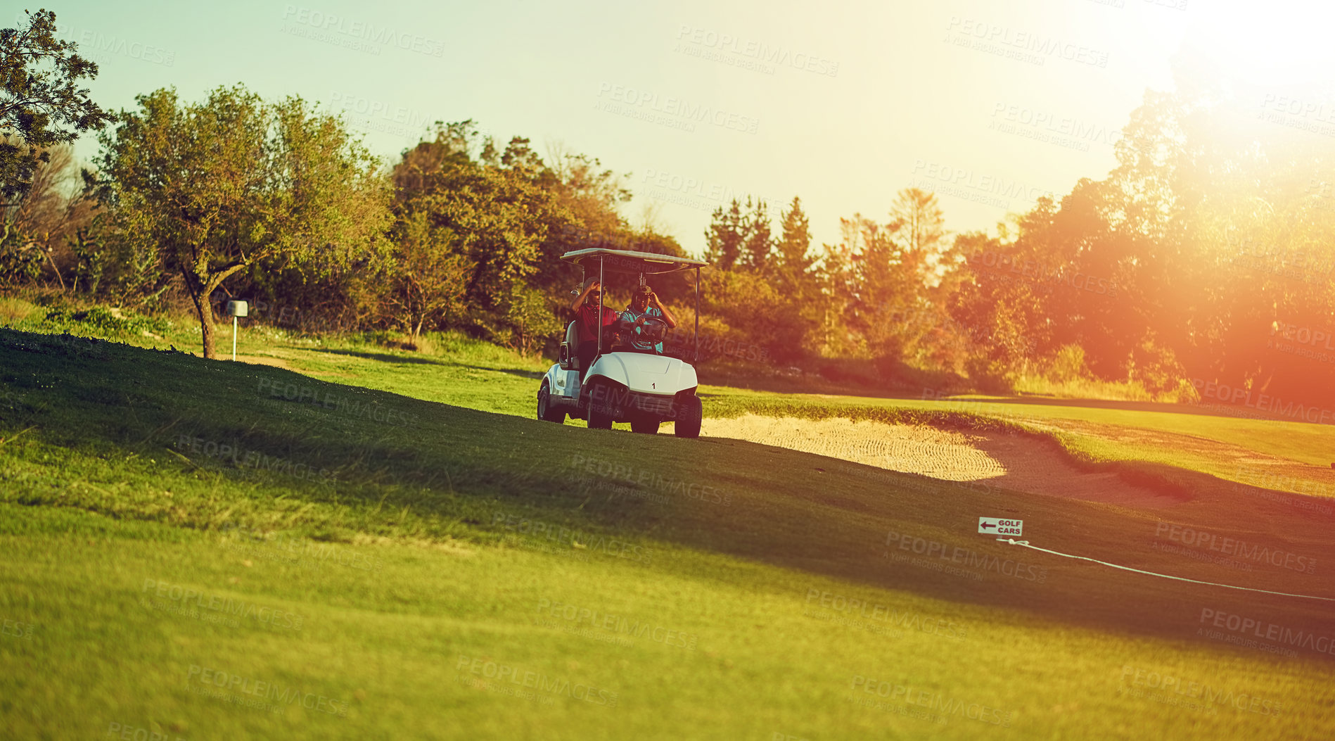 Buy stock photo Shot of two golfers riding in a cart on a golf course