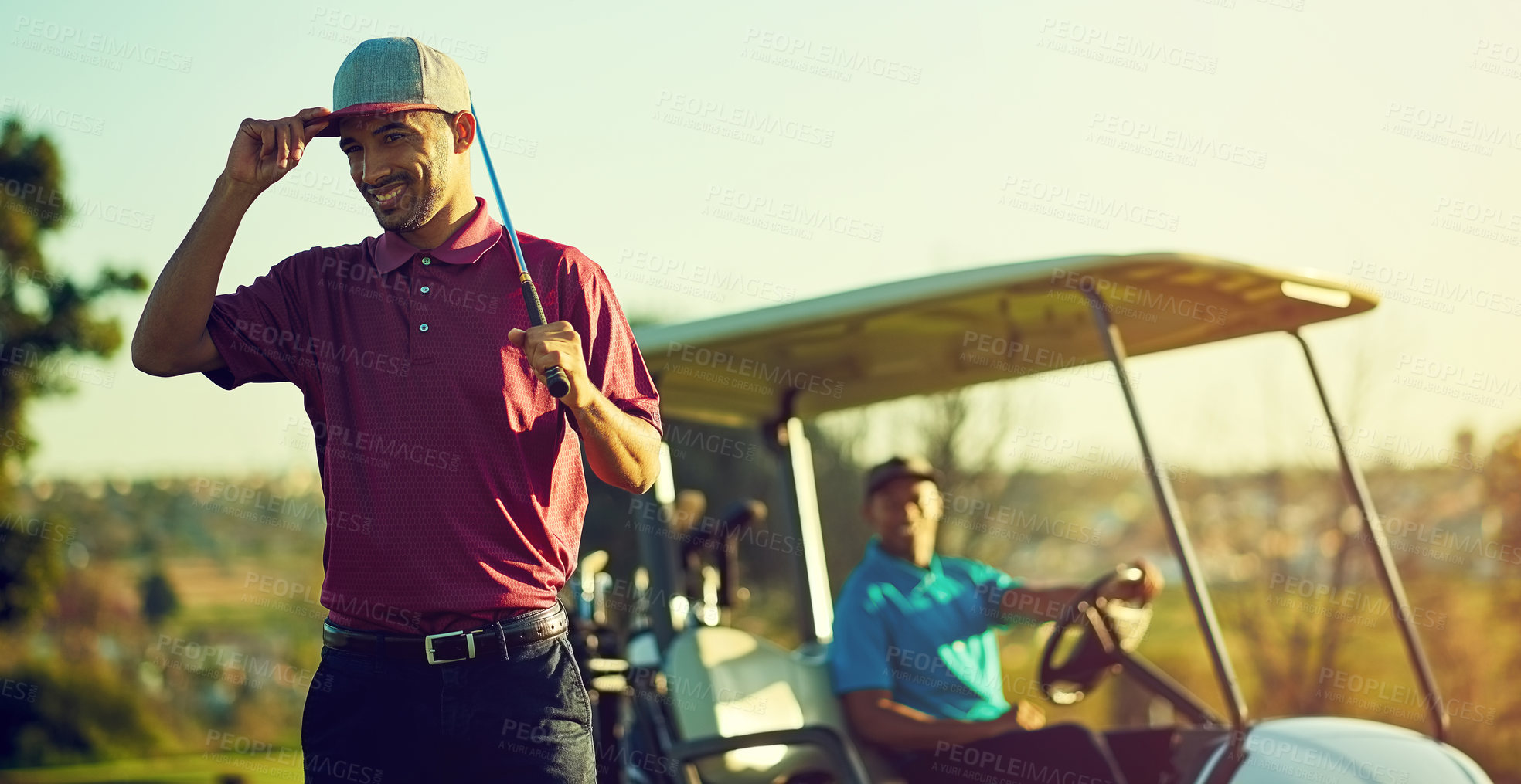 Buy stock photo Shot of a golfer holding his club with a buggy blurred in the background