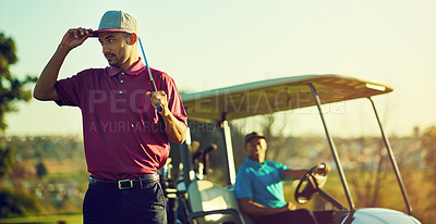 Buy stock photo Shot of a golfer holding his club with a buggy blurred in the background