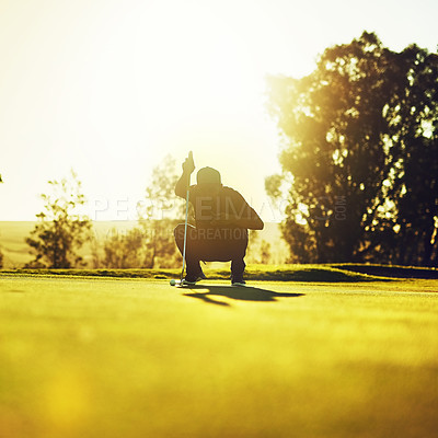 Buy stock photo Shot of a young man eyeing up the putt during a round of golf