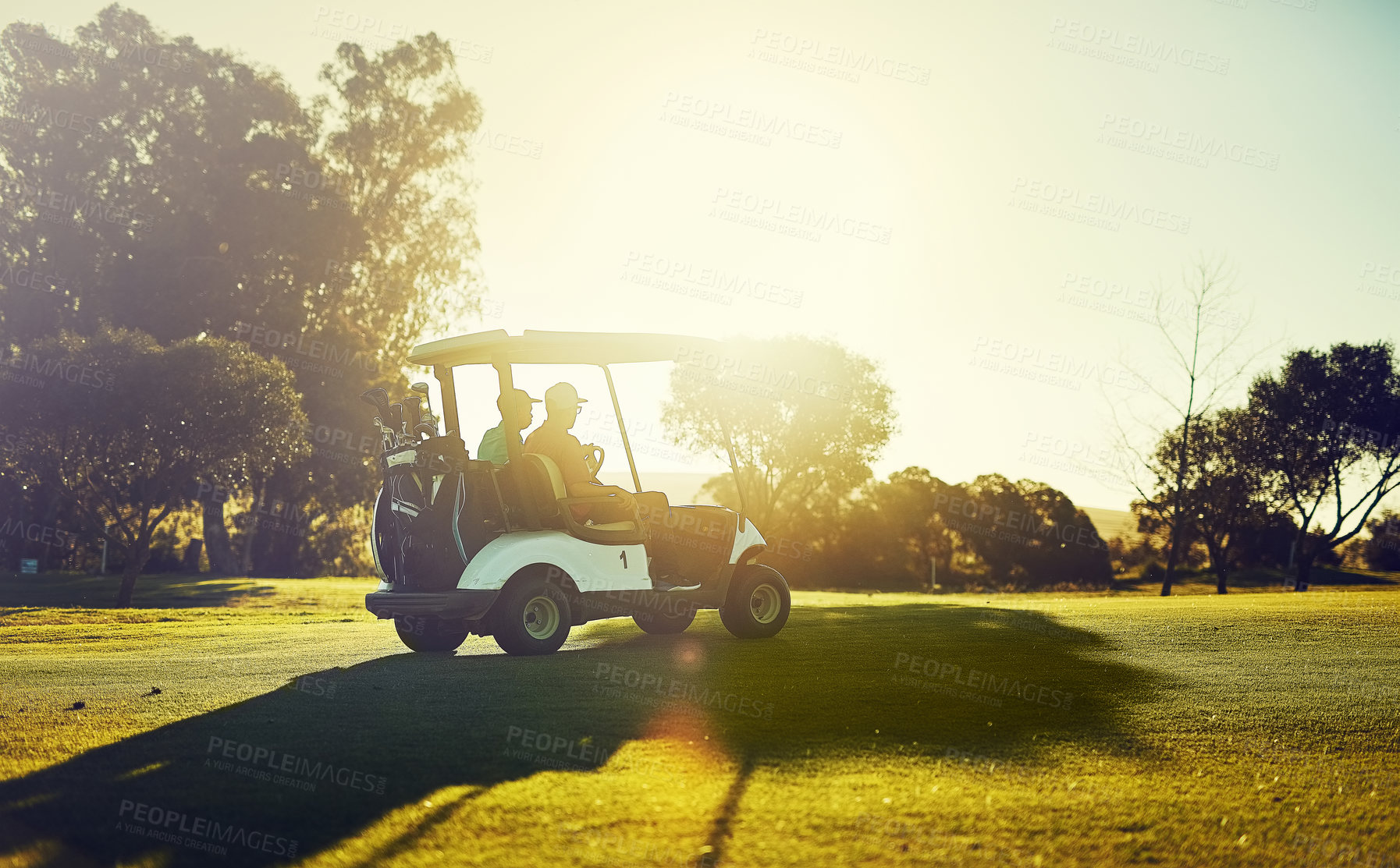 Buy stock photo Shot of two golfers riding in a cart on a golf course