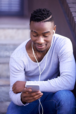 Buy stock photo Black man, cellphone and earphones for music in city on sitting on steps, streaming or connection. Male person, texting and social media scroll or downtown street in Atlanta, relax or subscription