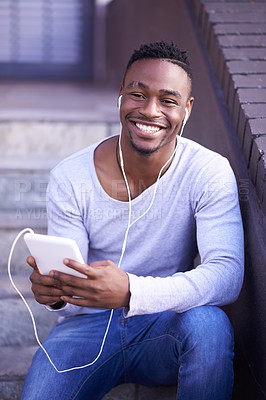 Buy stock photo Shot of a young man listening to music while sitting on a staircase outside