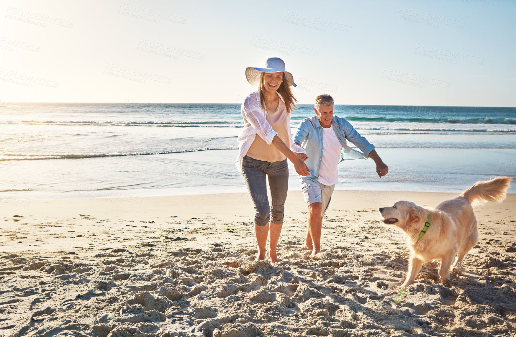 Buy stock photo Happy couple, holding hands and at the beach with a dog for walking and retirement travel in Indonesia. Smile, playful and elderly man and woman on a walk at the sea with a pet for play and holiday