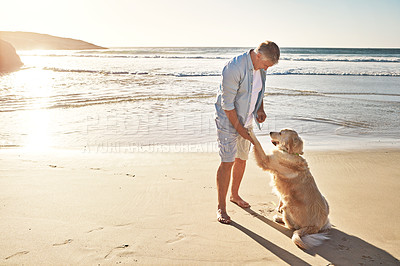 Buy stock photo Shot of a mature man taking his dog for a walk on the beach