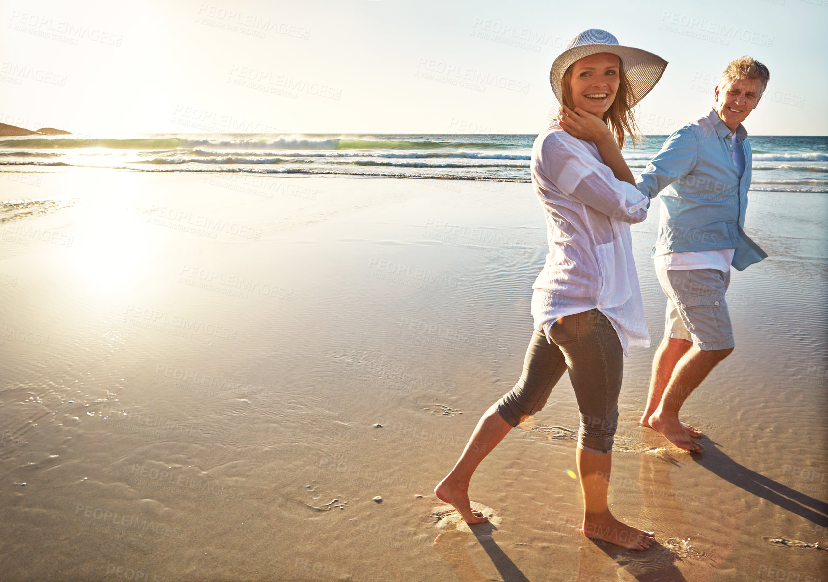 Buy stock photo Happy couple, walking and bonding on beach for vacation on island or coast for getaway, travel and holiday. Woman, man and relationship for love or marriage anniversary by ocean at sunrise in Bali