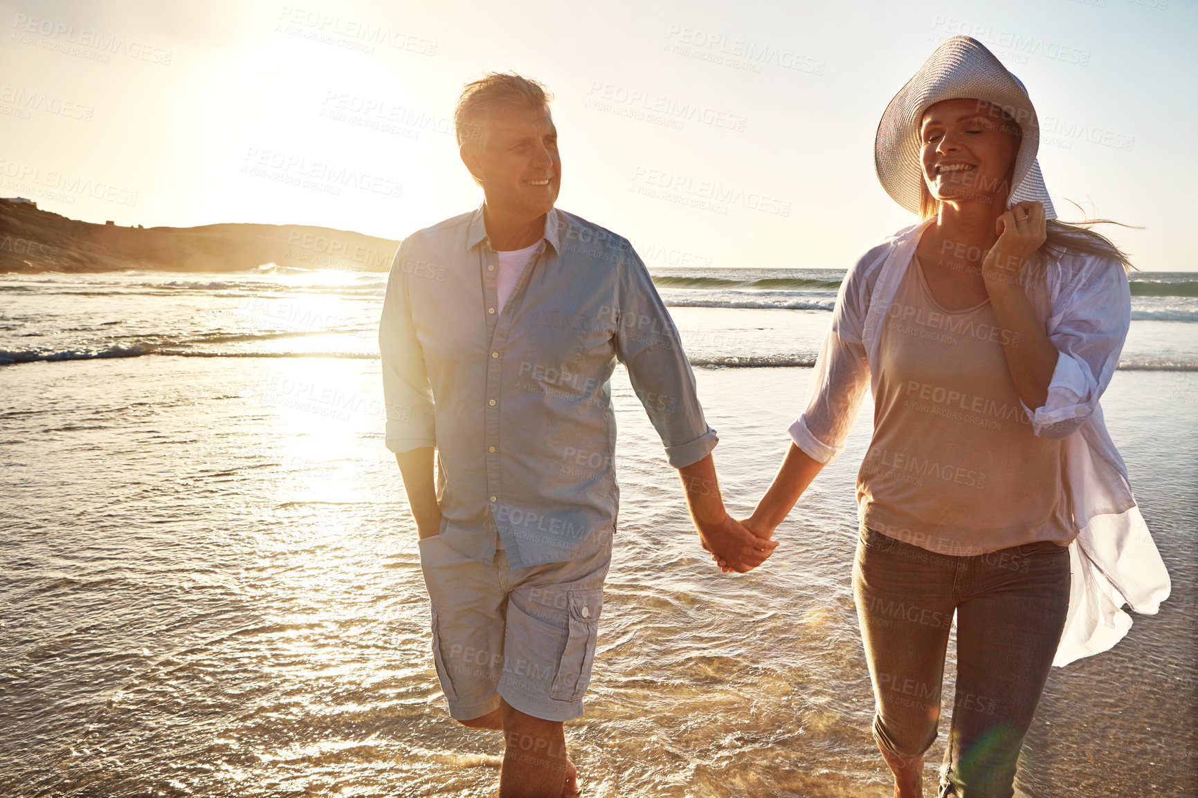 Buy stock photo Senior, happy couple and holding hands with relax on beach sunset for support, love or bonding in nature. Man, woman or lovers walking with smile on outdoor summer holiday by water or ocean coast