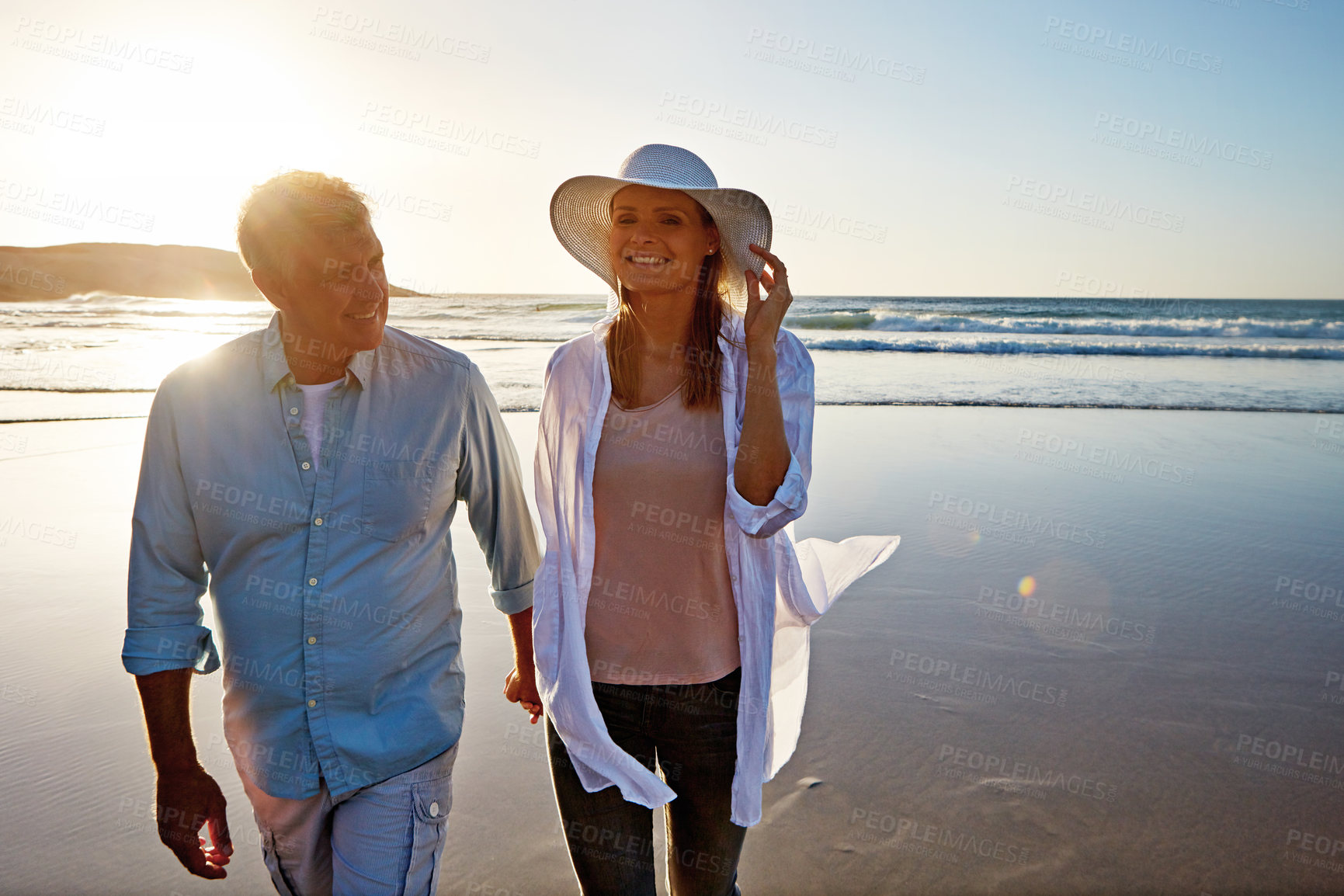 Buy stock photo Mature, happy couple and holding hands with beach sunset for love, embrace or bonding together in nature. Man, woman or lovers enjoying stroll with smile for outdoor holiday or summer by ocean coast