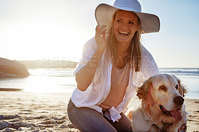 Buy stock photo Shot of a mature woman taking her dog for a walk on the beach