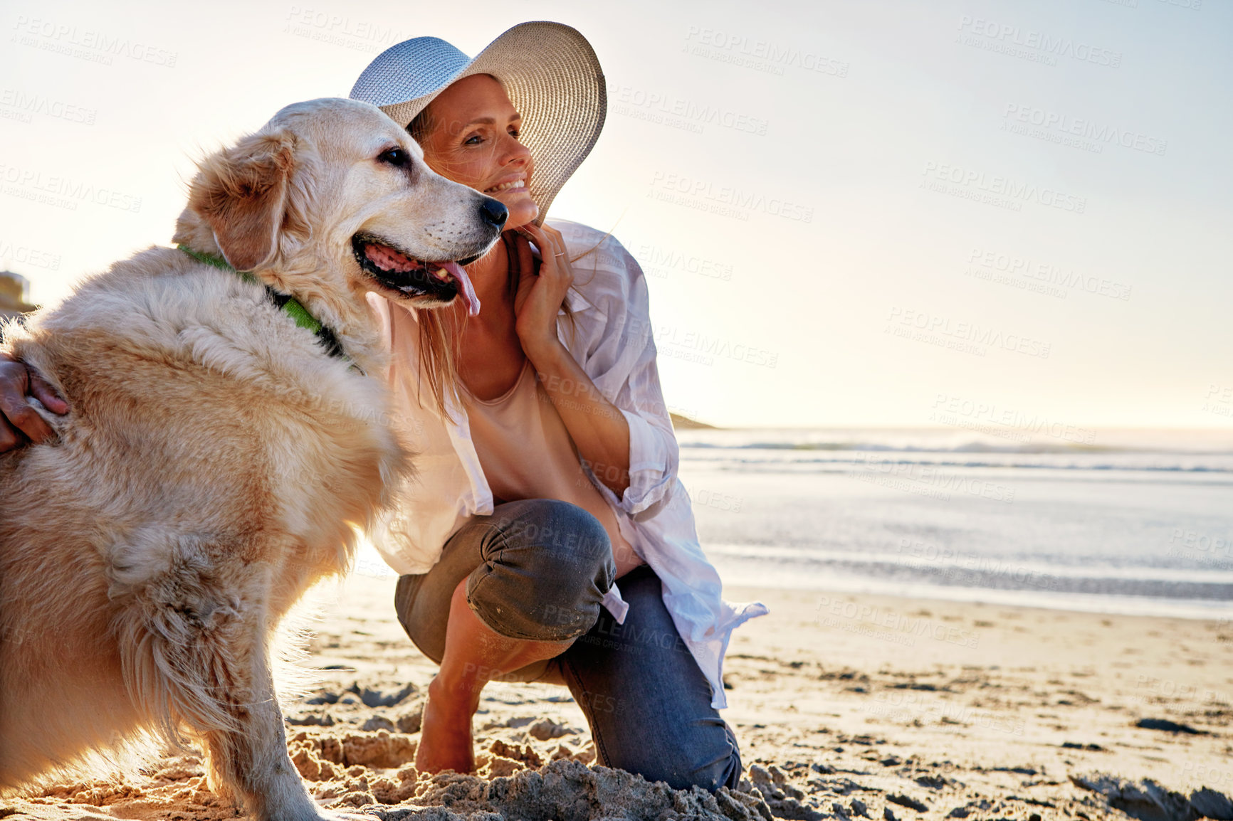 Buy stock photo Shot of a mature woman taking her dog for a walk on the beach