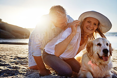 Buy stock photo Shot of a mature couple spending the day at the beach with their dog