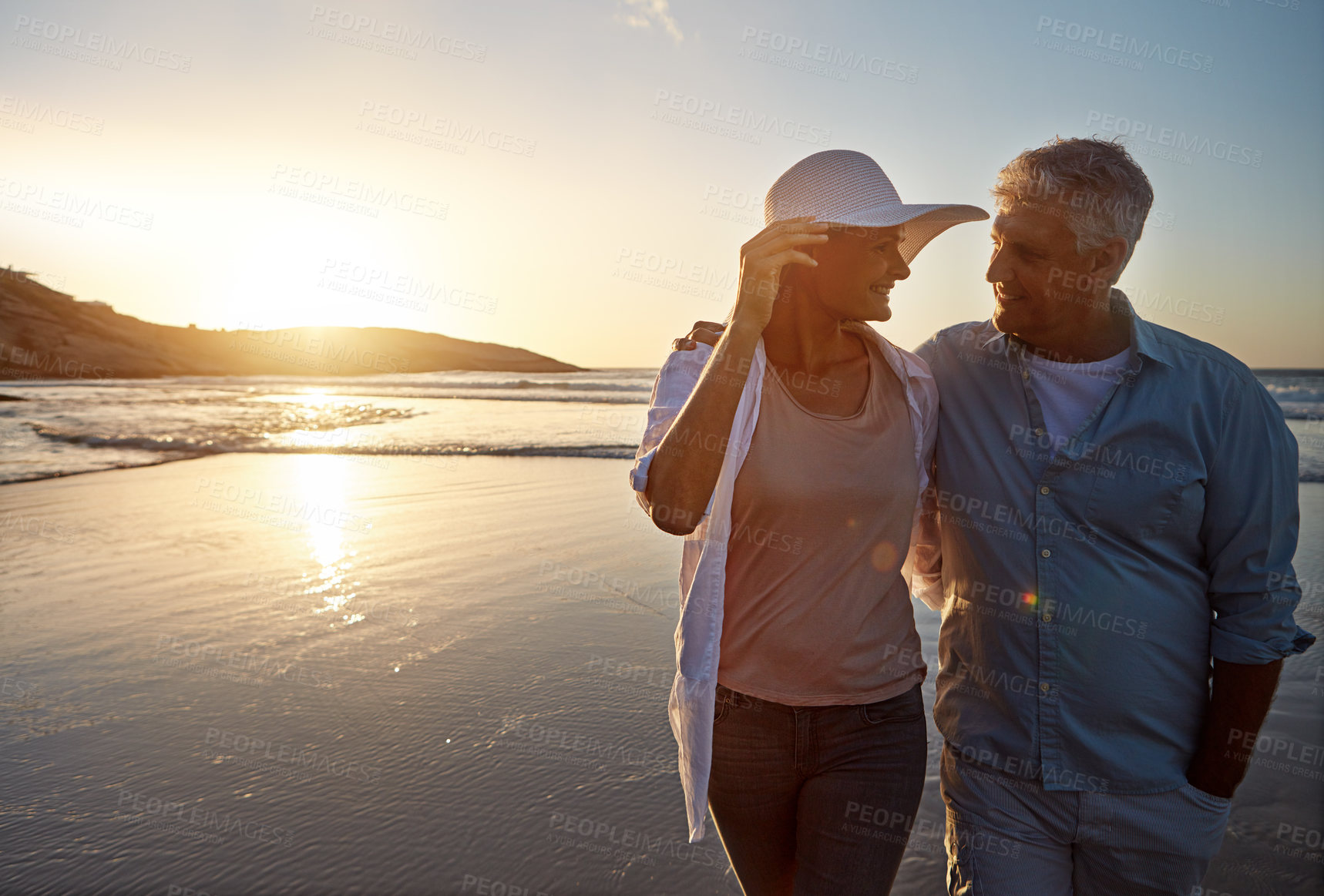 Buy stock photo Mature, happy couple and walking with hug on beach in sunset for love, embrace or bonding in nature. Man, woman or lovers enjoying romance, support or outdoor holiday for summer, water or ocean coast