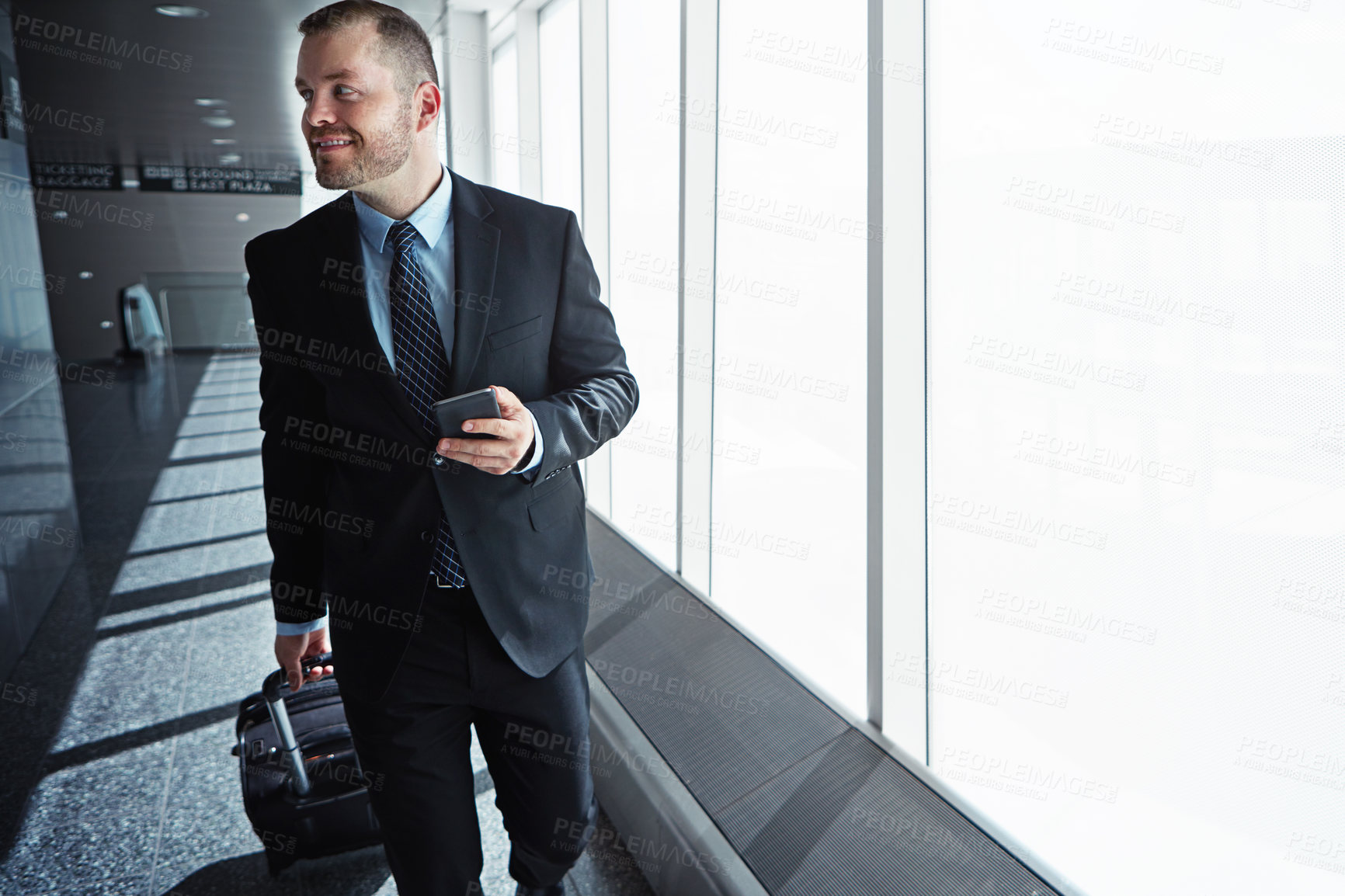 Buy stock photo Business man, smartphone and luggage in airport hallway with smile, thinking or idea for international travel. Entrepreneur, suitcase and phone with flight schedule for global immigration in London