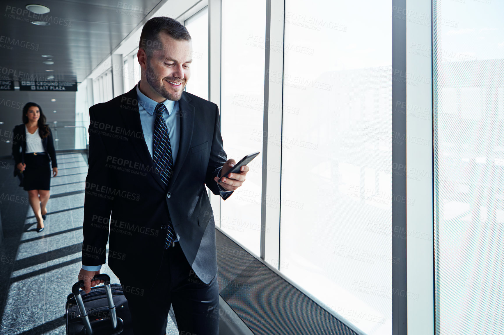 Buy stock photo Business man, phone and travel in airport window for reading, thinking and contact in corridor with smile. Entrepreneur, luggage and smartphone for flight schedule and global immigration in London