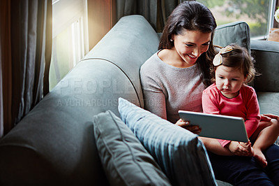 Buy stock photo Shot of a mother and her adorable little daughter using a digital tablet at home