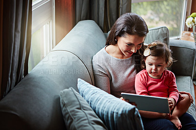 Buy stock photo Shot of a mother and her adorable little daughter using a digital tablet at home