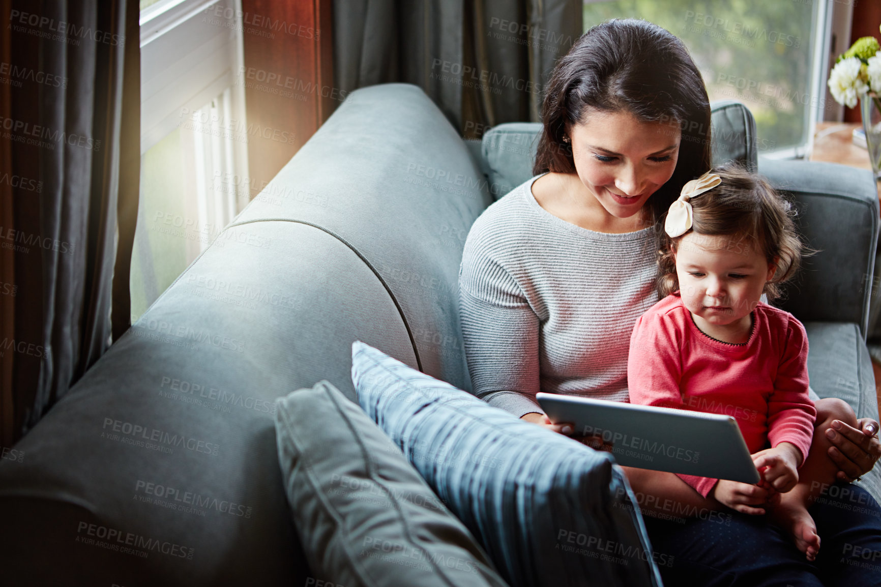 Buy stock photo Shot of a mother and her adorable little daughter using a digital tablet at home