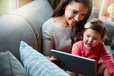 Buy stock photo Shot of a mother and her adorable little daughter using a digital tablet at home