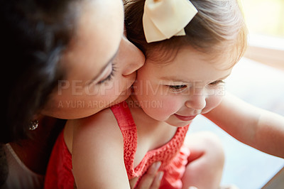 Buy stock photo Shot of a mother giving her adorable little daughter a kiss on the cheek at home