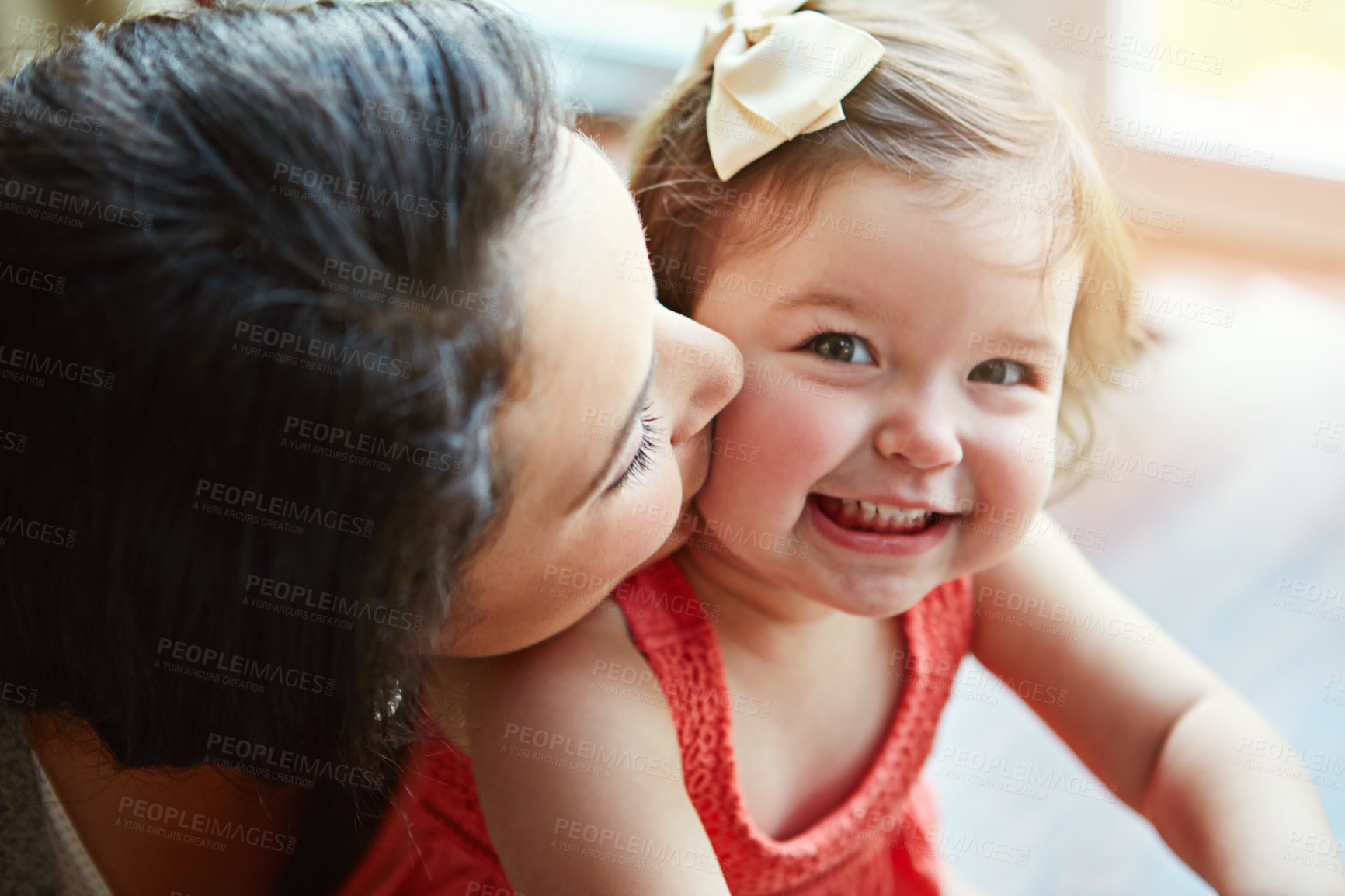 Buy stock photo Portrait of a baby with her mother kissing her cheek while playing, bonding and spending time together. Happy, smile and girl infant child sitting with her mom in their modern family home with love.