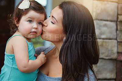 Buy stock photo Cropped shot of a mother giving her adorable little daughter a kiss on the cheek outside