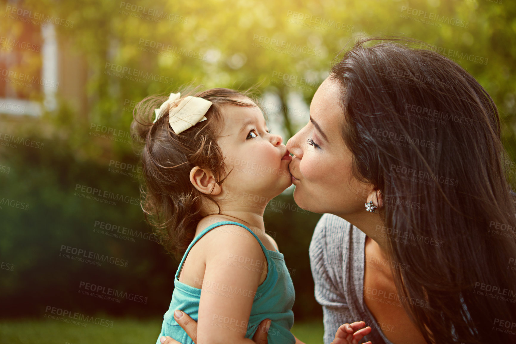 Buy stock photo Cropped shot of a mother giving her adorable little daughter a kiss outside