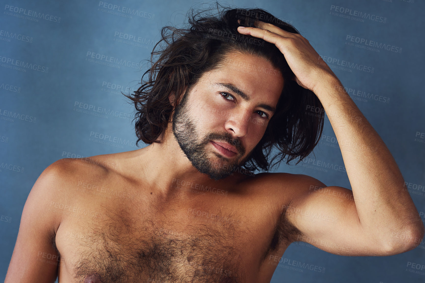 Buy stock photo Studio portrait of a handsome young man posing against a blue background