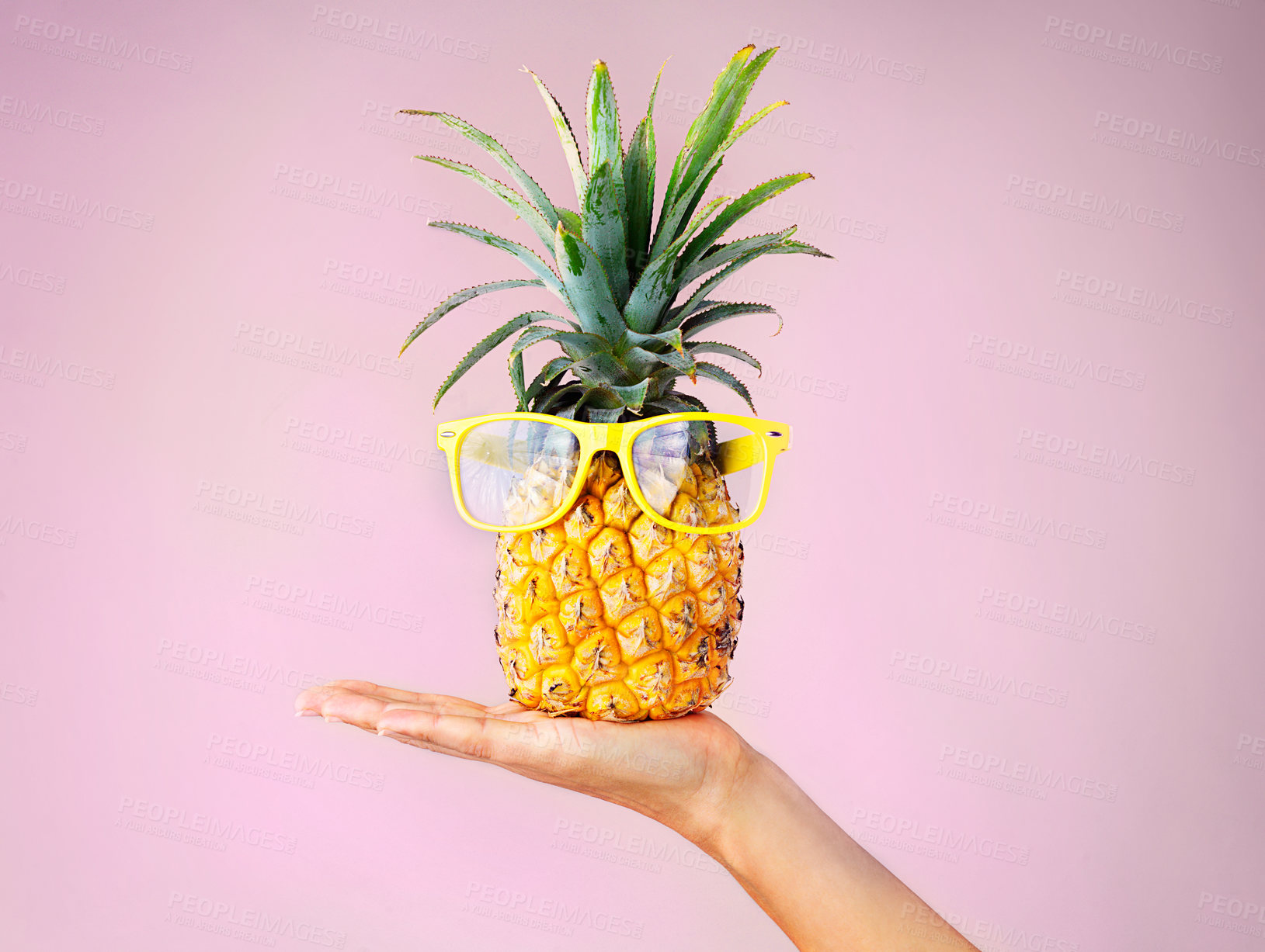 Buy stock photo Cropped shot of a woman holding a pineapple with glasses on against a pink background