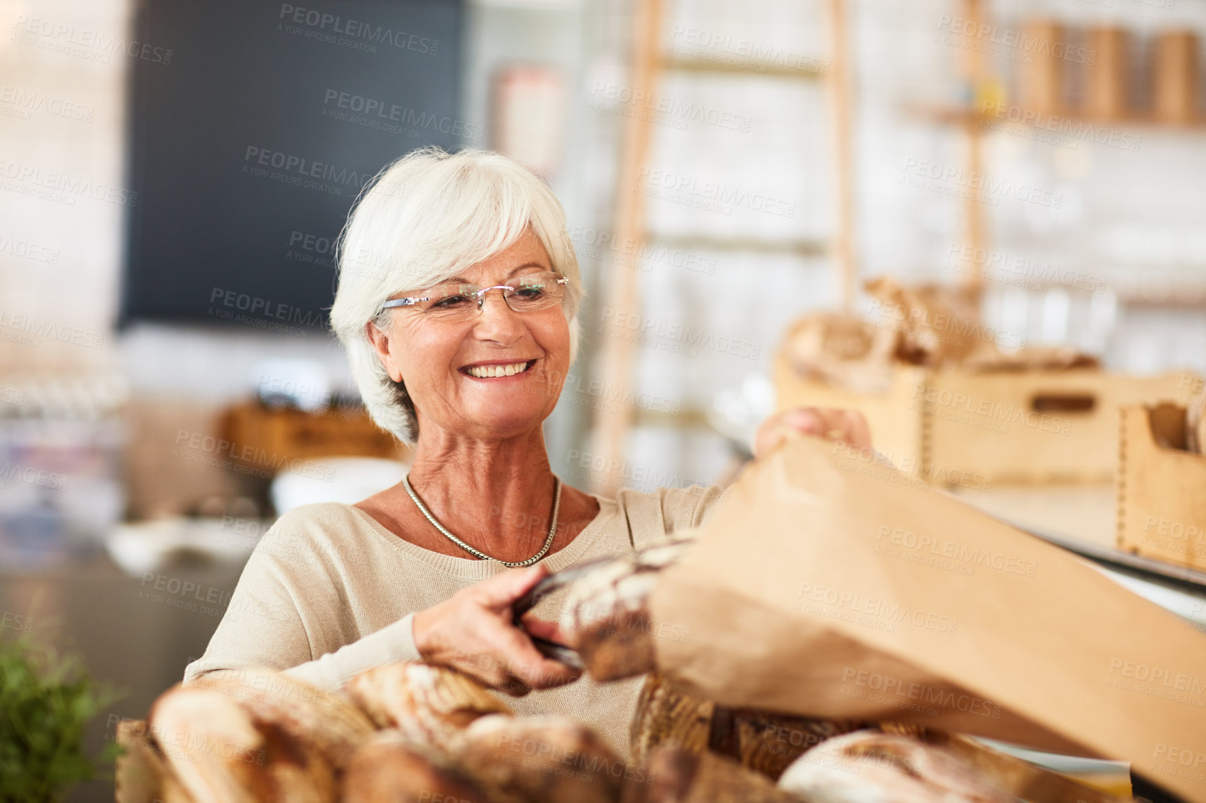 Buy stock photo Shot of a happy senior woman working in a bakery