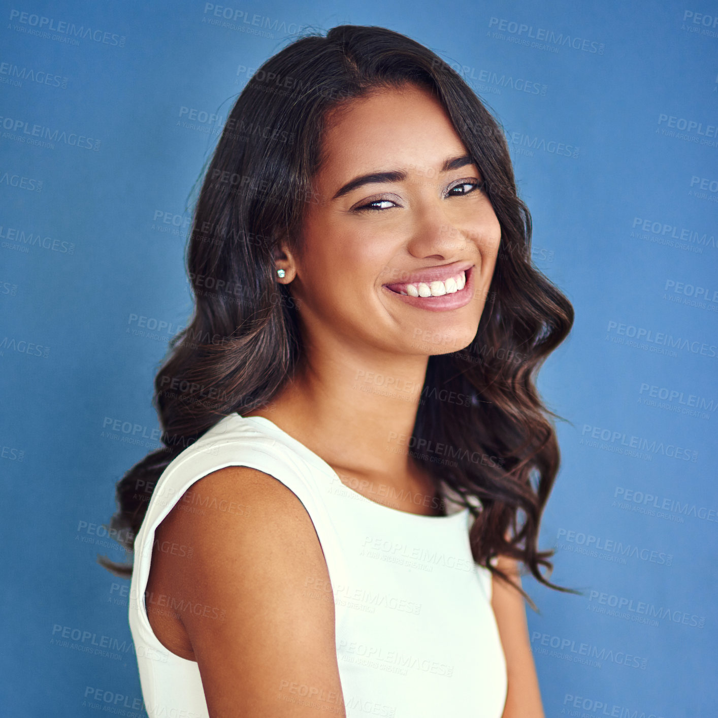 Buy stock photo Studio portrait of a confident young woman posing against a blue background
