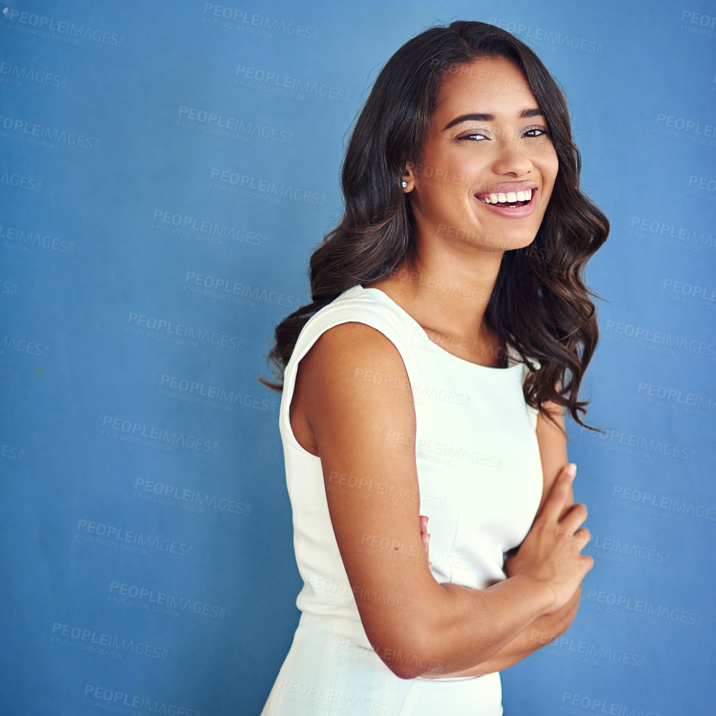 Buy stock photo Studio portrait of a confident young woman posing against a blue background