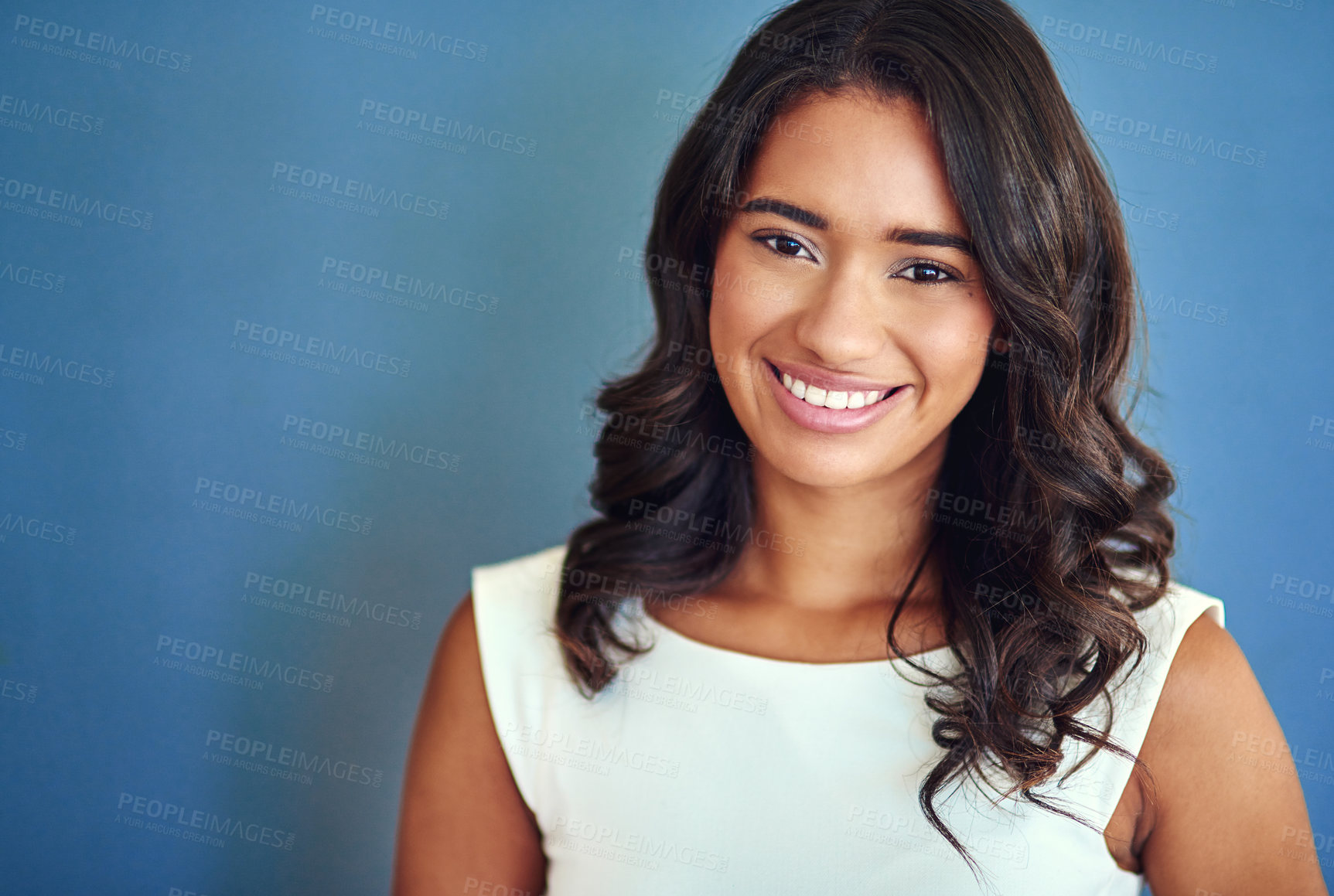 Buy stock photo Studio portrait of a confident young woman posing against a blue background