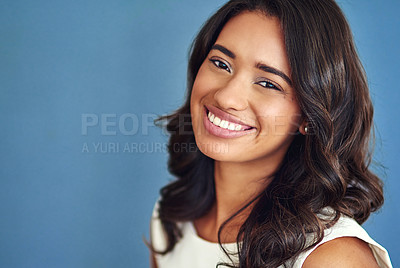 Buy stock photo Studio portrait of a confident young woman posing against a blue background
