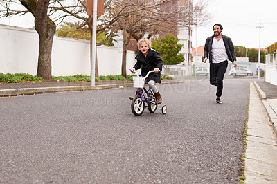 Buy stock photo Shot of a father teaching his little daughter how to ride a bicycle