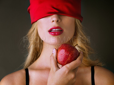 Buy stock photo Studio shot of a blindfolded young woman eating a red apple suggestively against a dark background