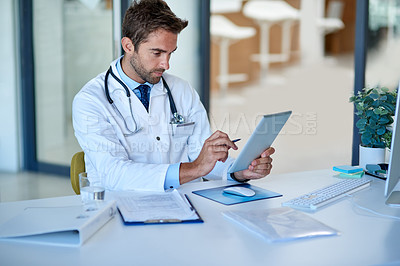 Buy stock photo Cropped shot of a young doctor working on a digital tablet in his office