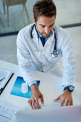 Buy stock photo High angle shot of a young doctor working on a computer in his office