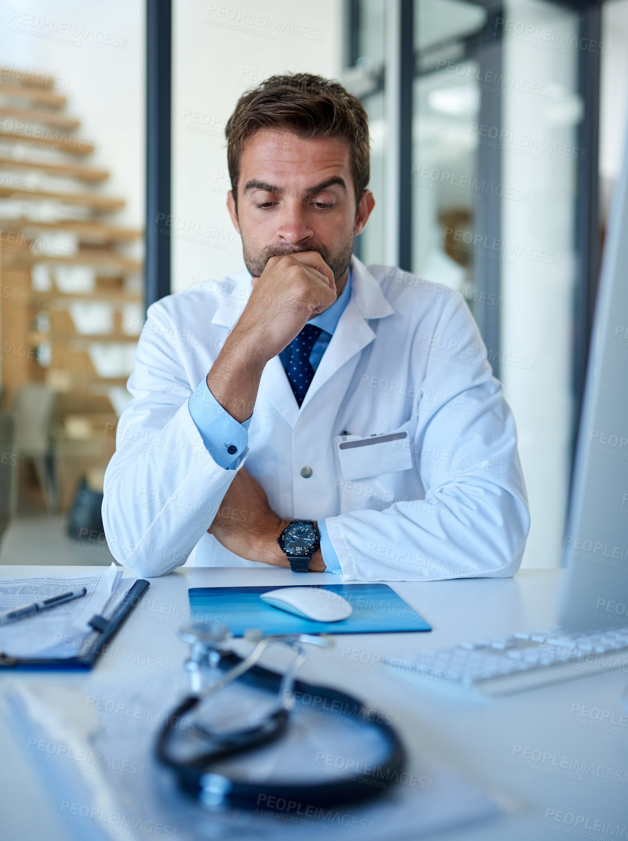 Buy stock photo Cropped shot of a young doctor looking stressed while working in his office