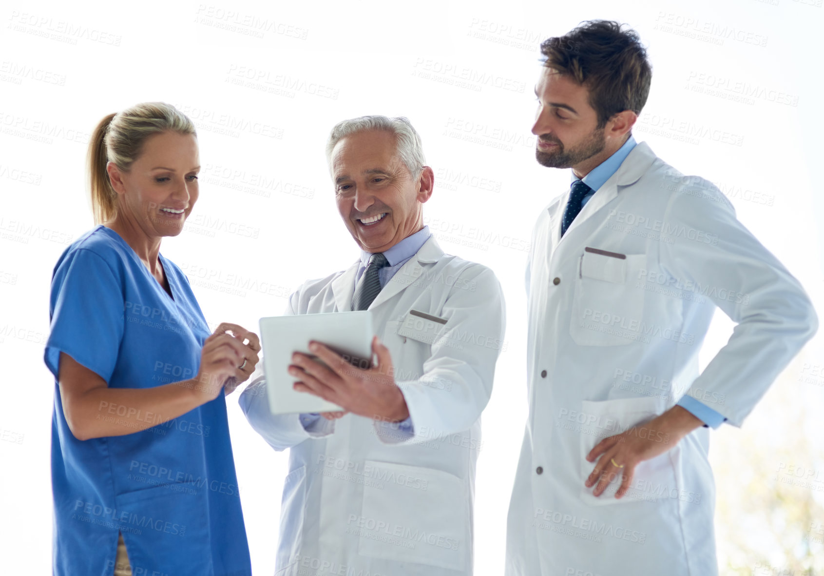 Buy stock photo Cropped shot of a group of medical practitioners discussing something on a digital tablet together