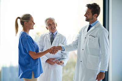 Buy stock photo Cropped shot of two medical practitioners shaking hands in a hospital
