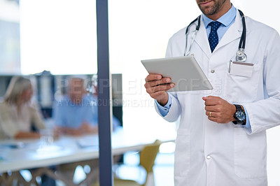 Buy stock photo Cropped shot of a doctor using a digital tablet with two patients sitting in the background