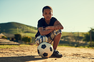 Buy stock photo Portrait of a little boy crouching on a field outside with a soccer ball