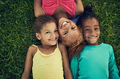 Buy stock photo High angle portrait of three little girls lying on the grass together outside