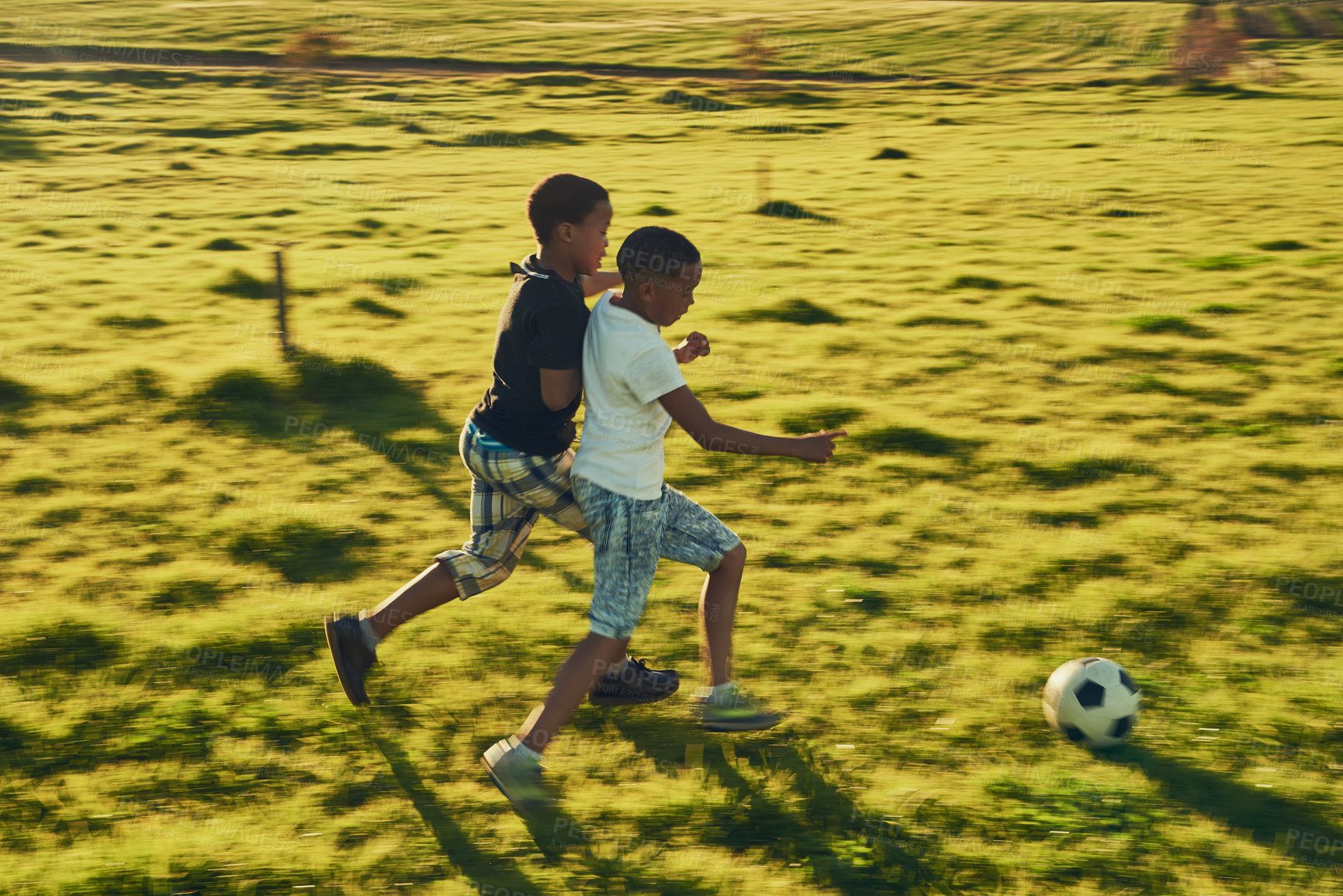 Buy stock photo Shot of a two children playing soccer together in a field outside