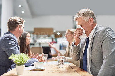 Buy stock photo Cropped shot of a businessman blowing his nose with his colleagues in the background
