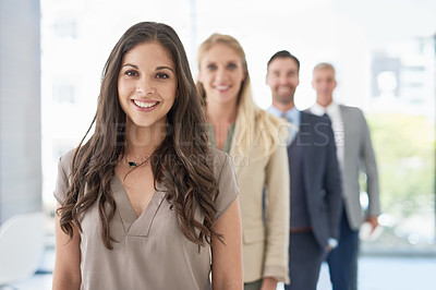 Buy stock photo Portrait of a young businesswoman standing in a line with her colleagues in an office