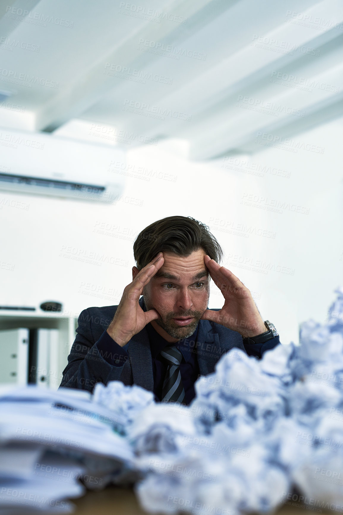 Buy stock photo Shot of a stressed out businessman sitting at his desk overwhelmed by paperwork