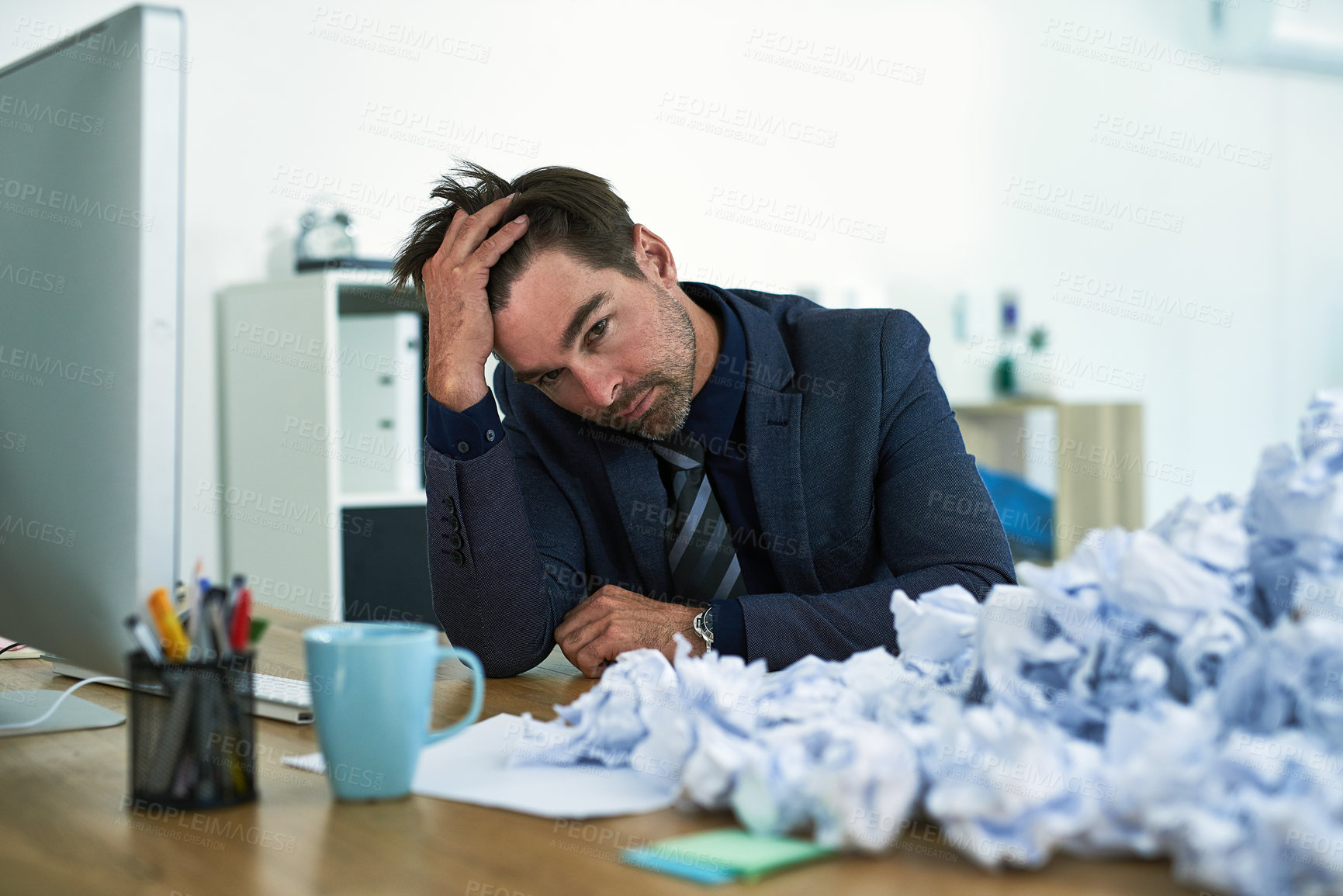 Buy stock photo Shot of a stressed out businessman sitting at his desk overwhelmed by paperwork