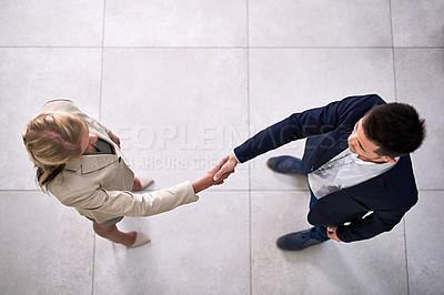 Buy stock photo High angle shot of two professional businesspeople shaking hands in the office