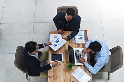 Buy stock photo High angle shot of three colleagues having a business meeting around a table in the office
